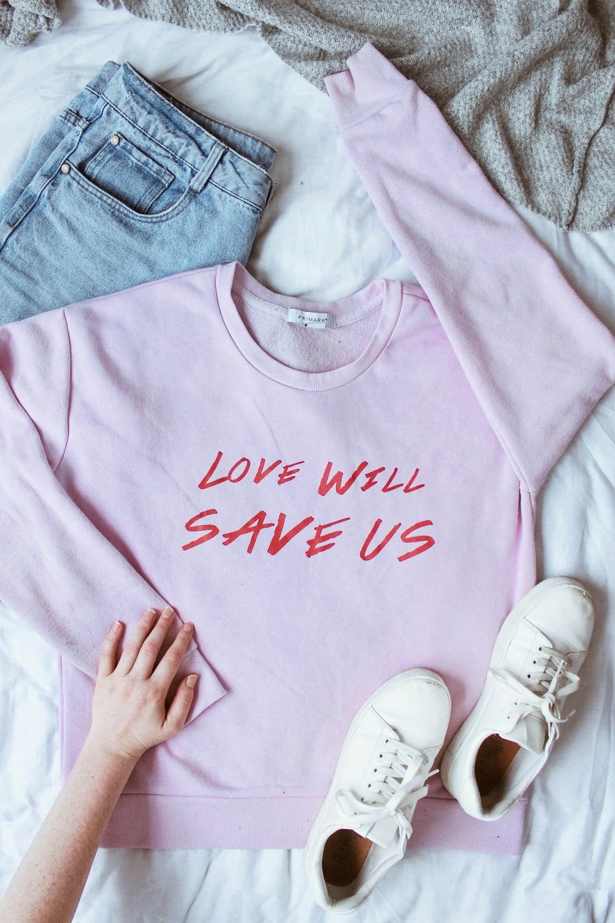 camisa lunga rosa su tessuto bianco vicino a sneakers bassi bianchi e pantaloncini denim blu