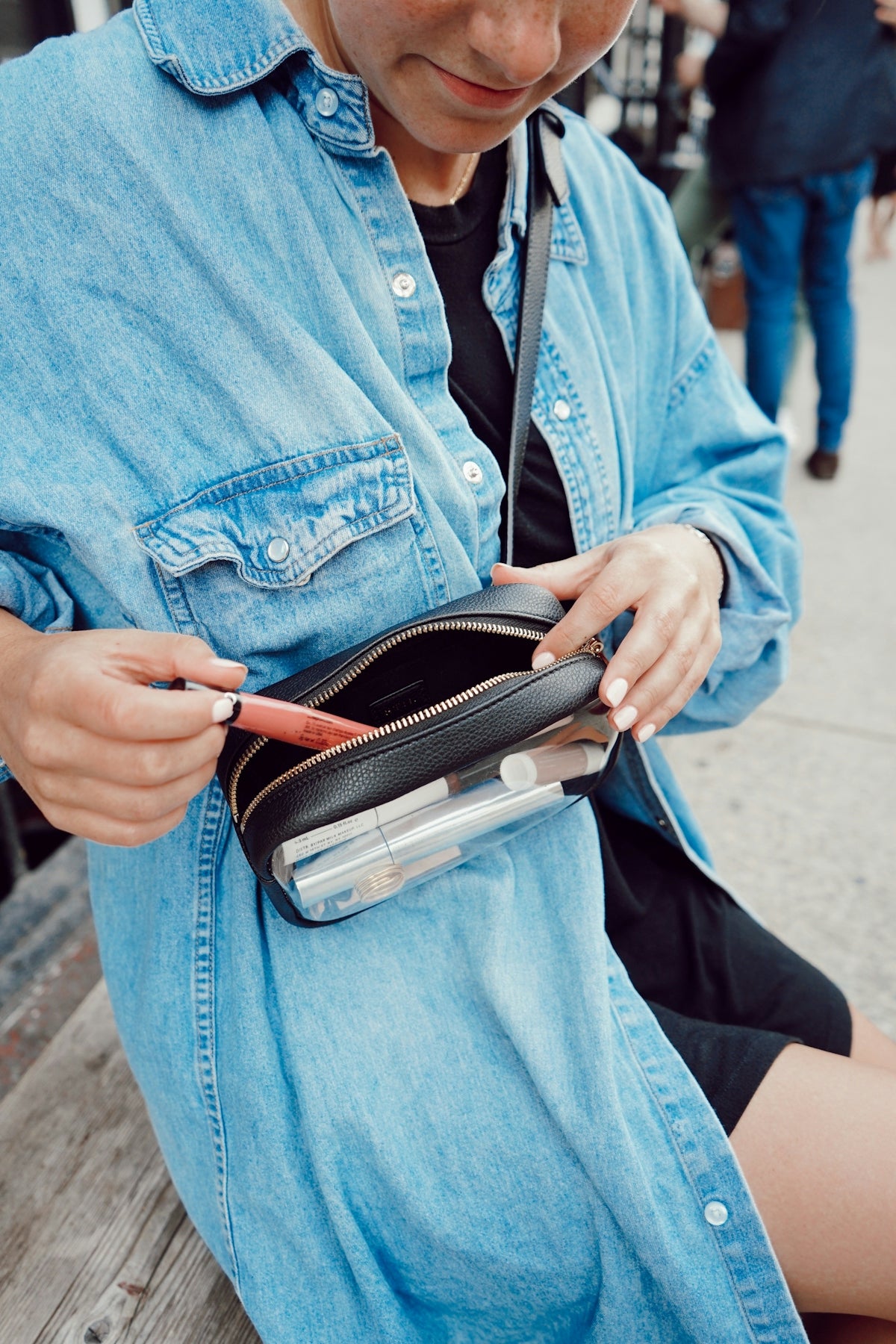 woman sitting and holding toiletry container in leather bag