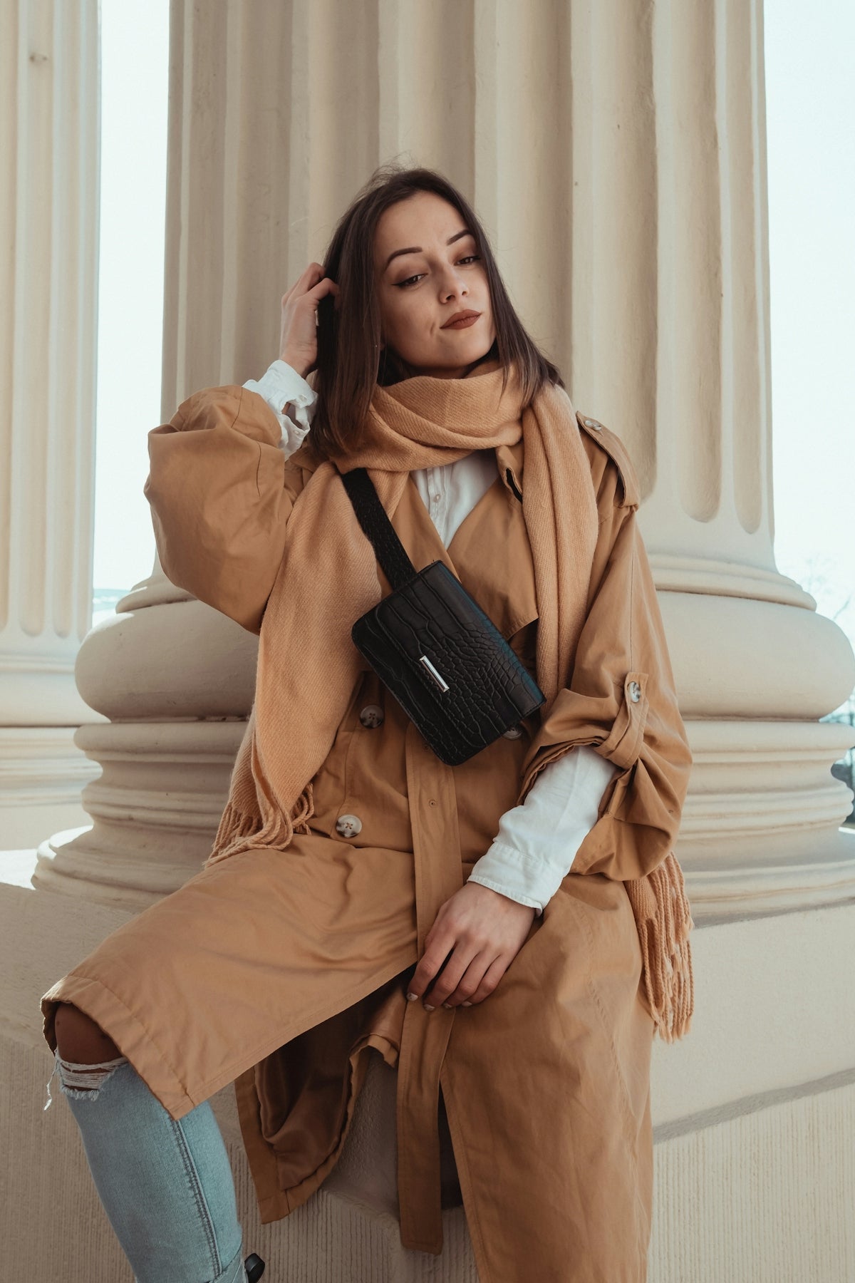 woman in brown coat holding black smartphone
