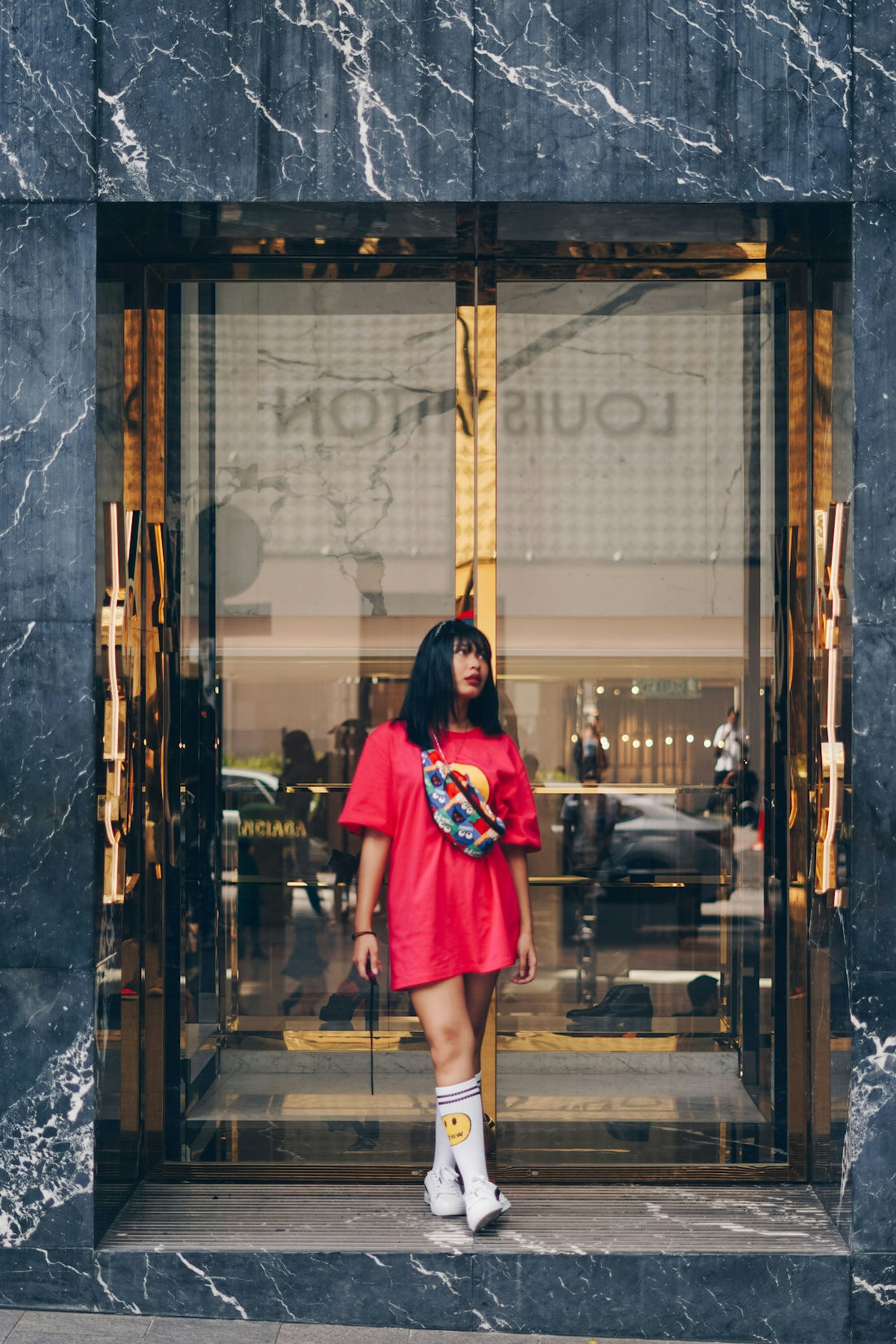 woman in red and black dress standing in front of glass window