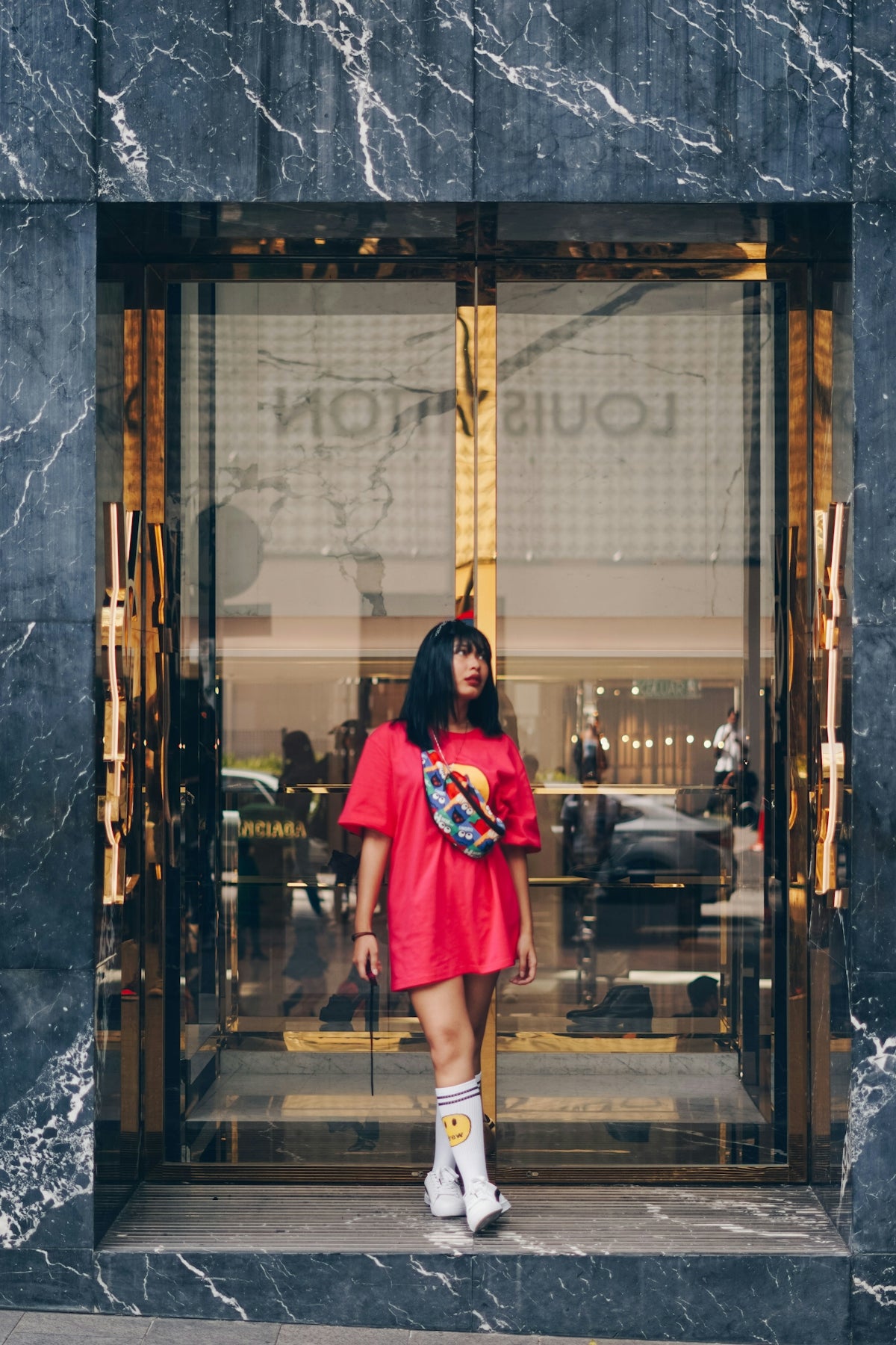 woman in red and black dress standing in front of glass window