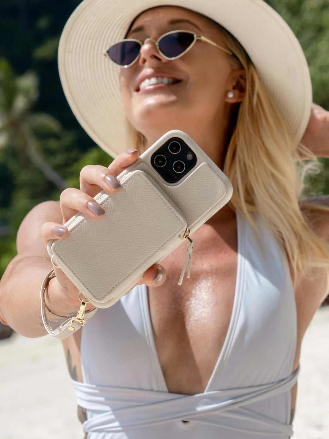 a woman wearing a hat and sunglasses holding a cell phone