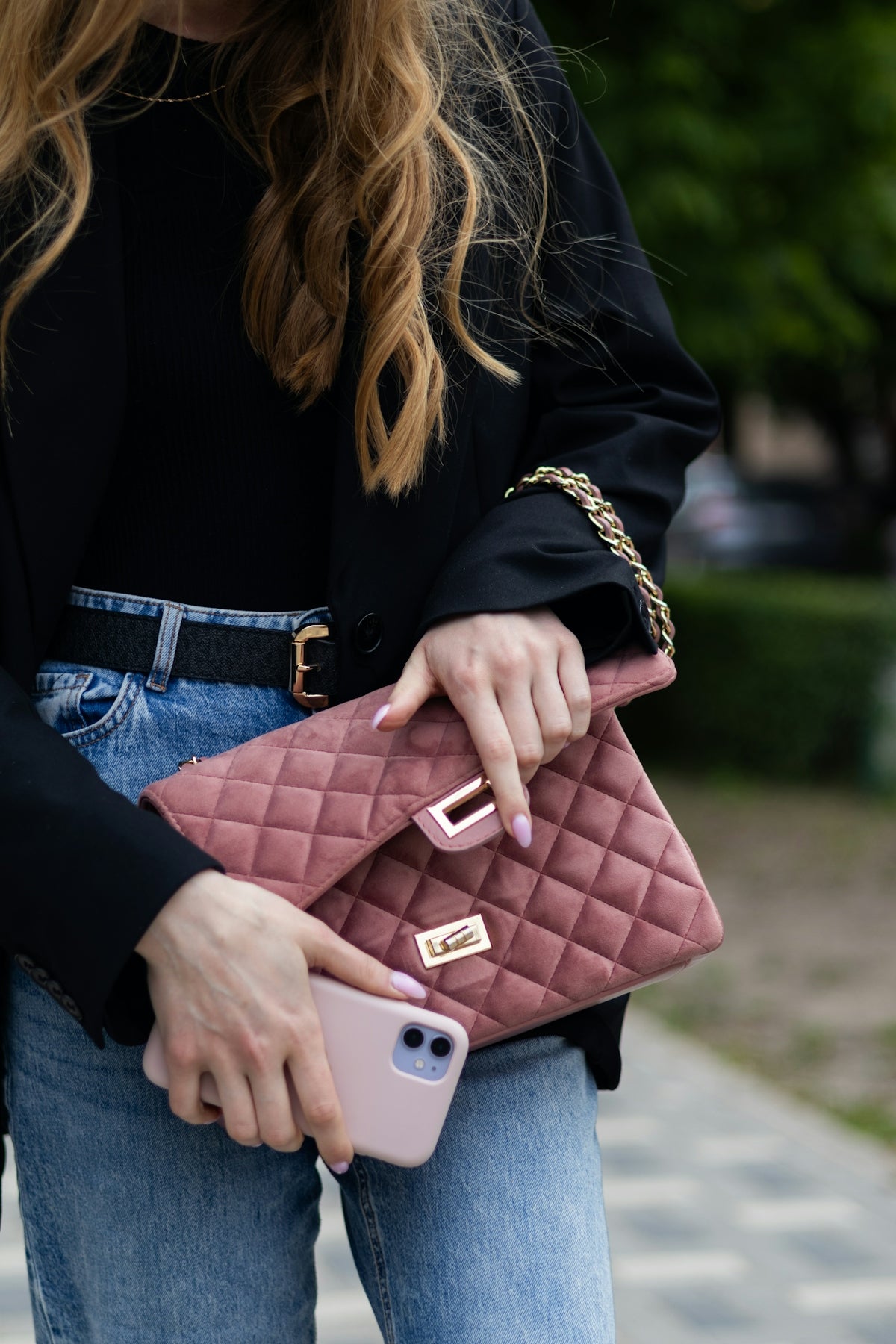 a woman holding a pink purse and a cell phone
