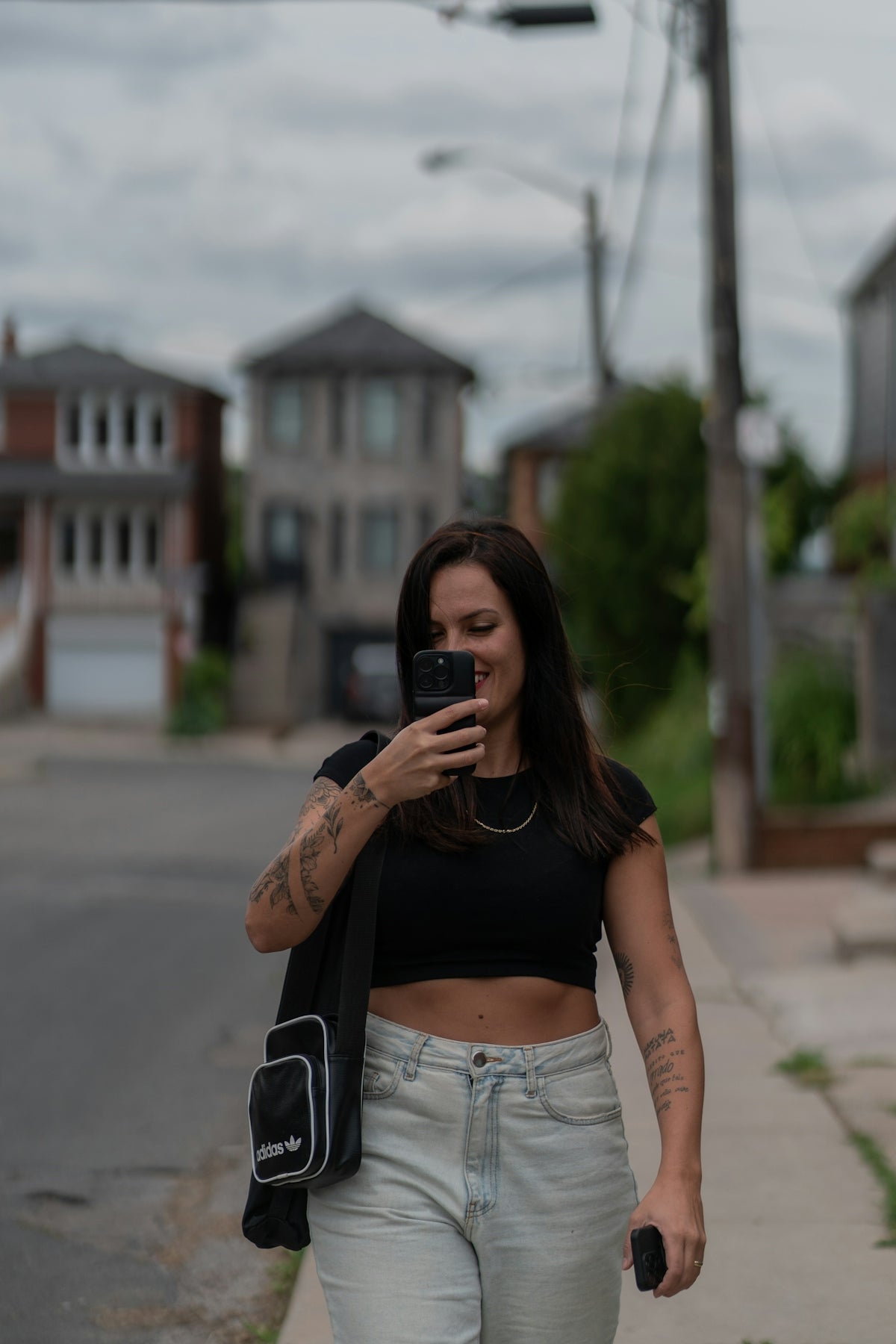 Una donna che cammina sulla strada tenendo un telefono cellulare