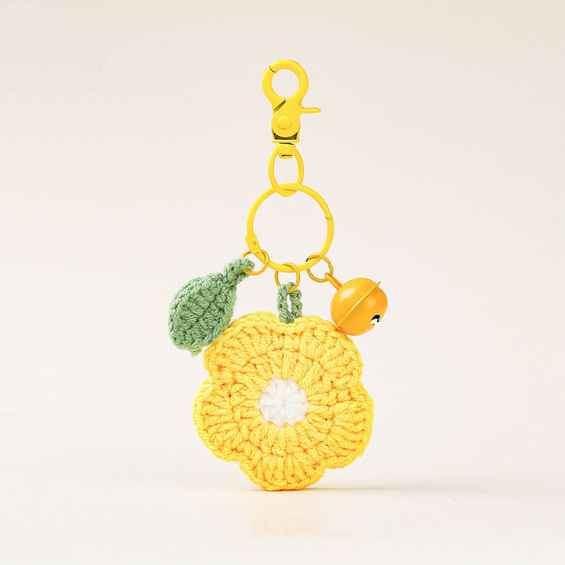 A yellow crochet flower keychain charm with a green leaf, a small yellow bell, and a gold clasp